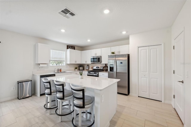 34797 Rainville Loop, Zephyrhills, FL 33541 - kitchen featuring stainless steel appliances, a center island, a kitchen breakfast bar, light countertops, and white cabinets
