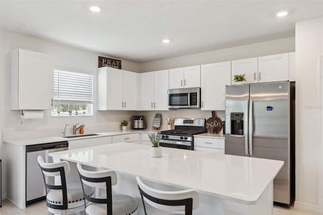 34797 Rainville Loop, Zephyrhills, FL 33541 - kitchen featuring appliances with stainless steel finishes, a sink, a kitchen bar, white cabinetry, and recessed lighting