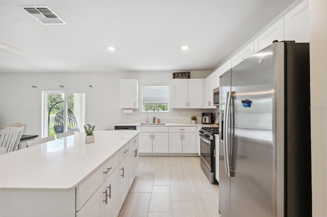 34797 Rainville Loop, Zephyrhills, FL 33541 - kitchen featuring stainless steel appliances, white cabinetry, light countertops, a kitchen island, and a sink