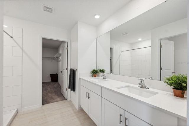34797 Rainville Loop, Zephyrhills, FL 33541 - bathroom with double vanity, a tile shower, a walk in closet, recessed lighting, and baseboards