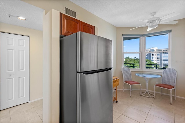 7932 Sailboat Key Blvd S Unit 406, South Pasadena, FL 33707 - kitchen with freestanding refrigerator, a textured ceiling, light tile patterned floors, ceiling fan, and brown cabinets