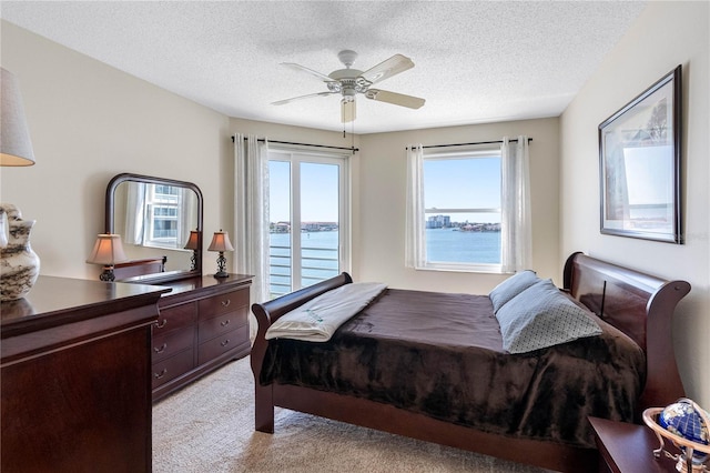7932 Sailboat Key Blvd S Unit 406, South Pasadena, FL 33707 - bedroom featuring light carpet, access to exterior, a textured ceiling, a ceiling fan, and a water view