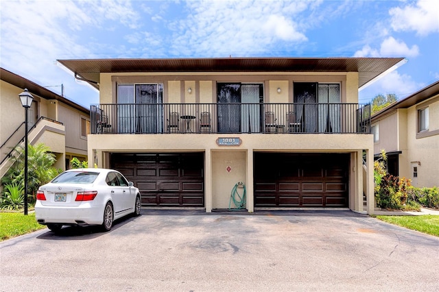 1881 Lichen Ln Unit B, Clearwater, FL 33760 - multi unit property with an attached garage, stucco siding, asphalt driveway, and a balcony