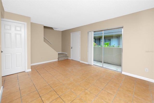 1881 Lichen Ln Unit B, Clearwater, FL 33760 - unfurnished room featuring stairway, light tile patterned floors, baseboards, and a textured ceiling