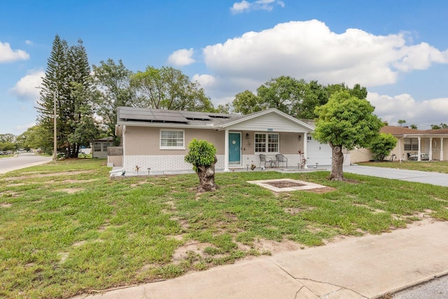 7901 Marlboro Dr, Port Richey, FL 34668 - ranch-style house with covered porch, brick siding, roof mounted solar panels, a front yard, and driveway