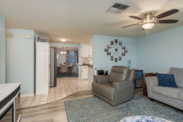 7901 Marlboro Dr, Port Richey, FL 34668 - living area featuring ceiling fan, light wood-style flooring, and a textured ceiling
