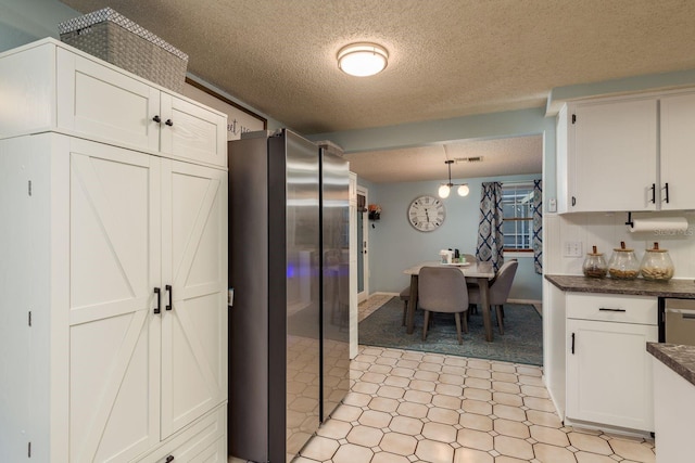 7901 Marlboro Dr, Port Richey, FL 34668 - kitchen with freestanding refrigerator, a textured ceiling, dark countertops, white cabinetry, and pendant lighting