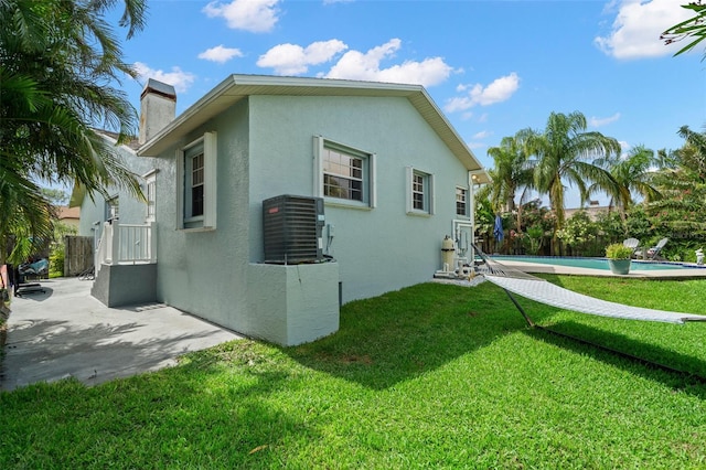 338 7th Ave N, Tierra Verde, FL 33715 - view of property exterior featuring stucco siding, central AC unit, a chimney, and a patio area