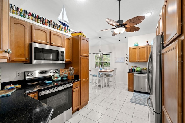 338 7th Ave N, Tierra Verde, FL 33715 - kitchen with stainless steel appliances, brown cabinets, ceiling fan, light tile patterned floors, and dark stone counters