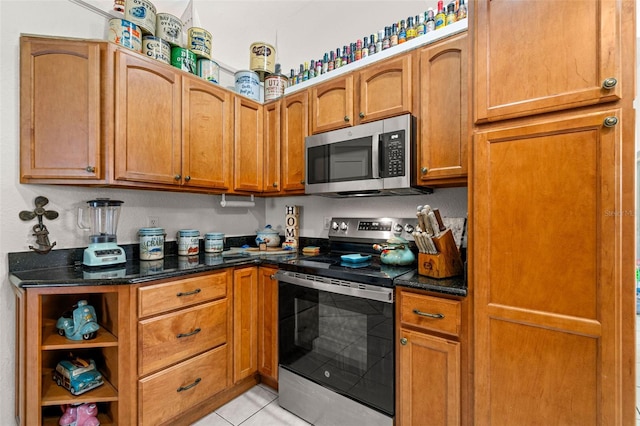 338 7th Ave N, Tierra Verde, FL 33715 - kitchen featuring appliances with stainless steel finishes, dark stone countertops, light tile patterned floors, and brown cabinets