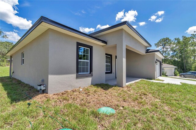 2705 W Royal Palm Dr, Citrus Springs, FL 34434 - view of home's exterior with stucco siding, a lawn, and an attached garage