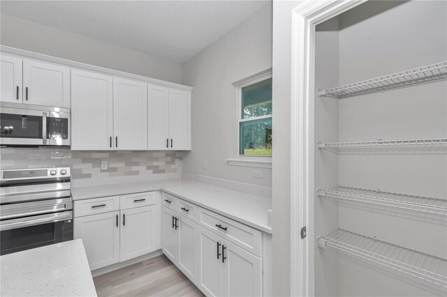2705 W Royal Palm Dr, Citrus Springs, FL 34434 - kitchen featuring appliances with stainless steel finishes, white cabinetry, tasteful backsplash, and light wood finished floors