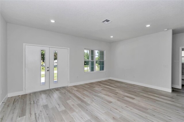 2705 W Royal Palm Dr, Citrus Springs, FL 34434 - spare room featuring light wood-style flooring, french doors, a textured ceiling, recessed lighting, and a smoke detector