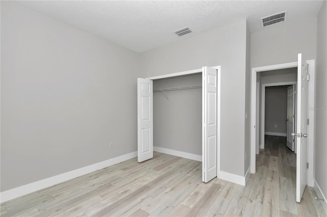 2705 W Royal Palm Dr, Citrus Springs, FL 34434 - unfurnished bedroom featuring light wood-style flooring, a closet, and a textured ceiling