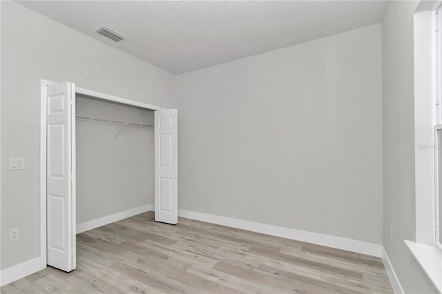 2705 W Royal Palm Dr, Citrus Springs, FL 34434 - unfurnished bedroom with light wood-style flooring, a closet, and a textured ceiling