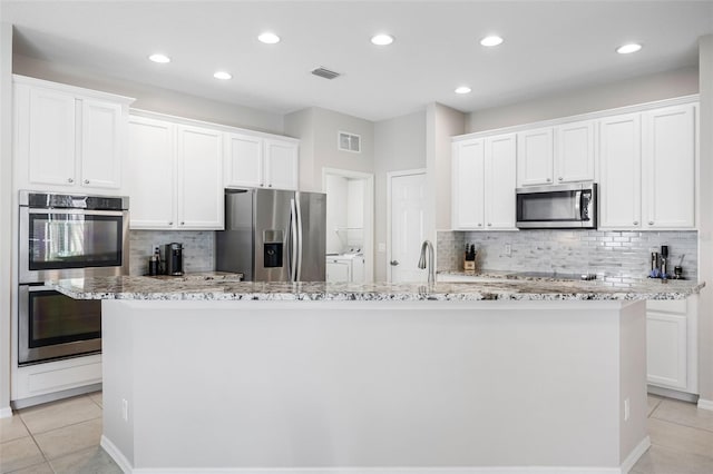 1178 Fraser Pine Blvd, Sarasota, FL 34240 - kitchen featuring appliances with stainless steel finishes, separate washer and dryer, tasteful backsplash, a kitchen island with sink, and light tile patterned flooring