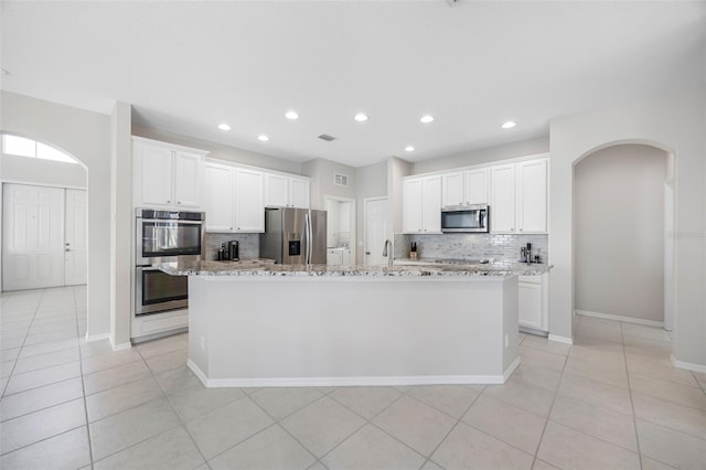 1178 Fraser Pine Blvd, Sarasota, FL 34240 - kitchen with appliances with stainless steel finishes, arched walkways, backsplash, a kitchen island with sink, and recessed lighting