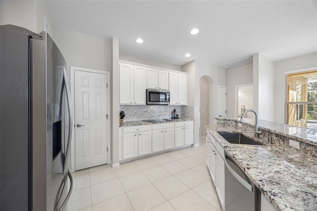 1178 Fraser Pine Blvd, Sarasota, FL 34240 - kitchen with appliances with stainless steel finishes, a sink, arched walkways, tasteful backsplash, and white cabinetry