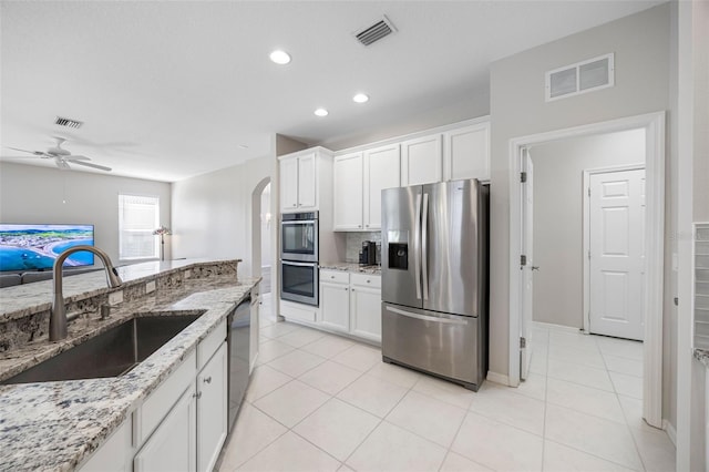 1178 Fraser Pine Blvd, Sarasota, FL 34240 - kitchen with appliances with stainless steel finishes, a sink, arched walkways, a ceiling fan, and white cabinets