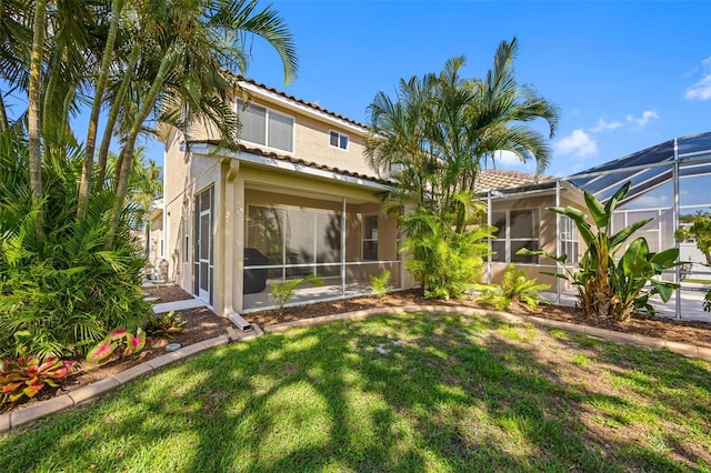 1178 Fraser Pine Blvd, Sarasota, FL 34240 - rear view of property with a tiled roof, a yard, stucco siding, and glass enclosure