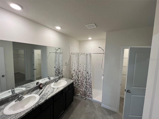 8210 Juning Cv, Wesley Chapel, FL 33545 - full bath with a spacious closet, a tile shower, double vanity, tile patterned floors, and a textured ceiling
