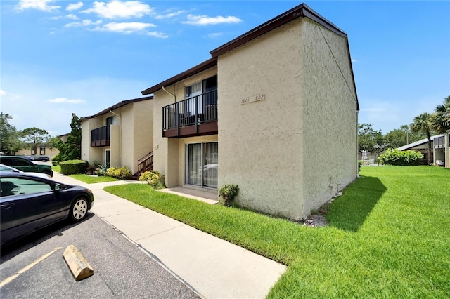 4215 E Bay Dr Unit 1801E, Clearwater, FL 33764 - view of home's exterior featuring stucco siding, a lawn, uncovered parking, and a balcony
