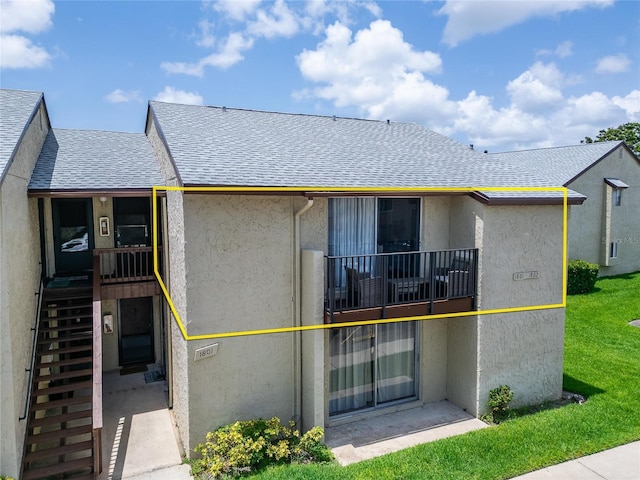 4215 E Bay Dr Unit 1801E, Clearwater, FL 33764 - rear view of property featuring roof with shingles, stucco siding, a balcony, and stairs