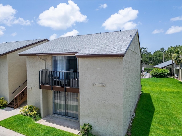 4215 E Bay Dr Unit 1801E, Clearwater, FL 33764 - rear view of house with stucco siding, a yard, roof with shingles, and a balcony