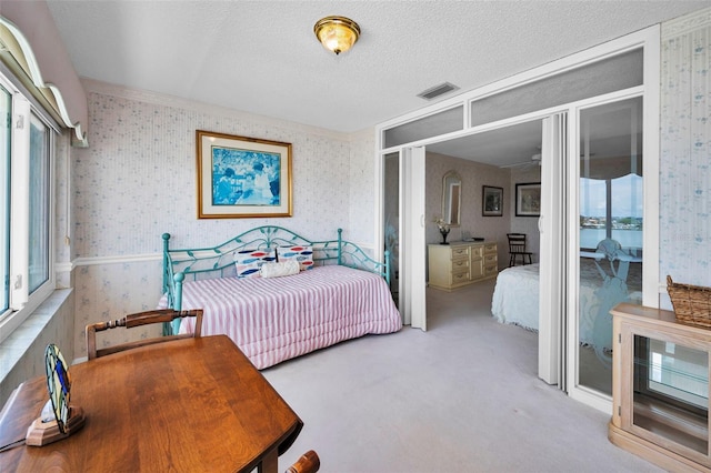 100 Bluff View Dr Unit 511C, Belleair Bluffs, FL 33770 - carpeted bedroom with wallpapered walls, multiple windows, and a textured ceiling