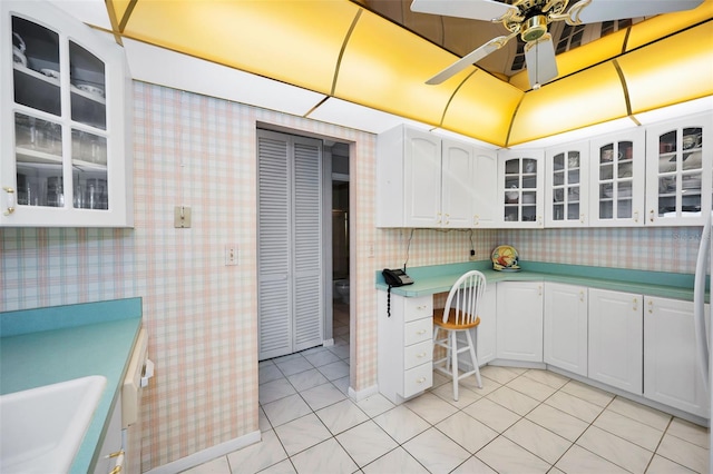 100 Bluff View Dr Unit 511C, Belleair Bluffs, FL 33770 - kitchen with wallpapered walls, a ceiling fan, light countertops, white cabinets, and glass insert cabinets