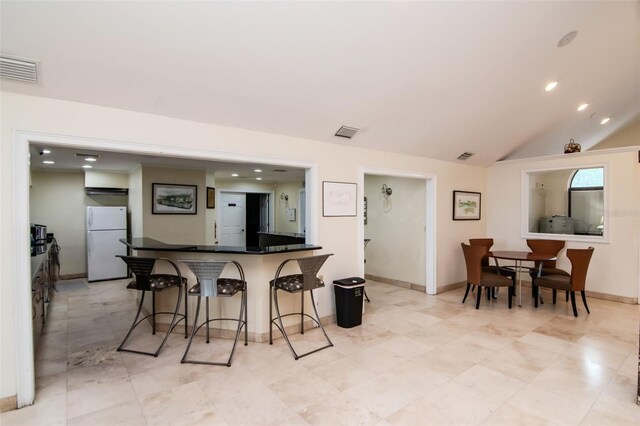 10265 Gandy Blvd N Unit 1702, Saint Petersburg, FL 33702 - kitchen featuring freestanding refrigerator, a kitchen bar, dark countertops, lofted ceiling, and recessed lighting