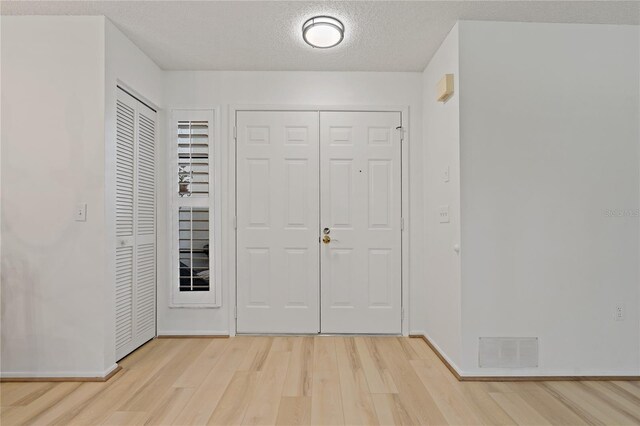 1401 Camelot Ct, Palm Harbor, FL 34684 - entrance foyer featuring light wood-style floors, baseboards, and a textured ceiling