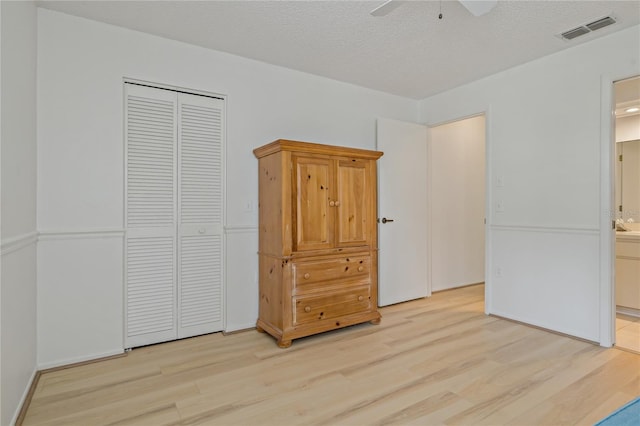 1401 Camelot Ct, Palm Harbor, FL 34684 - unfurnished bedroom with light wood-type flooring, ensuite bathroom, a closet, a textured ceiling, and a ceiling fan