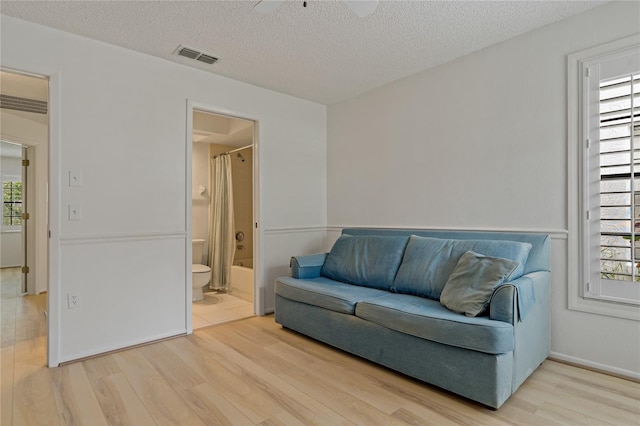 1401 Camelot Ct, Palm Harbor, FL 34684 - living room featuring light wood-style flooring, a textured ceiling, and ceiling fan
