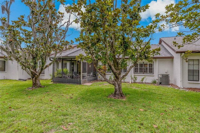 1401 Camelot Ct, Palm Harbor, FL 34684 - rear view of house with cooling unit, a sunroom, stucco siding, and a yard