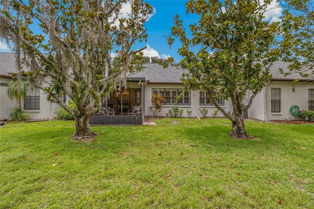 1401 Camelot Ct, Palm Harbor, FL 34684 - back of property featuring stucco siding, a yard, a sunroom, and roof with shingles