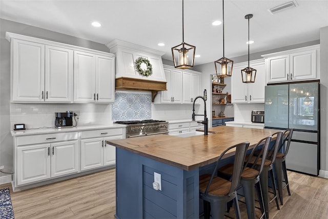 7570 Sweeter Tide Trl, Wesley Chapel, FL 33545 - kitchen with freestanding refrigerator, high end stainless steel range, wooden counters, light wood-style flooring, and backsplash