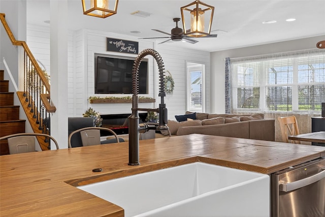 7570 Sweeter Tide Trl, Wesley Chapel, FL 33545 - kitchen featuring butcher block counters, dishwasher, ceiling fan, open floor plan, and a glass covered fireplace