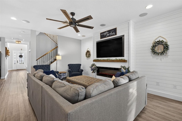 7570 Sweeter Tide Trl, Wesley Chapel, FL 33545 - living room with a ceiling fan, stairs, wood finished floors, recessed lighting, and a glass covered fireplace