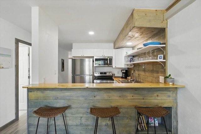 511 1st St, Cedar Key, FL 32625 - kitchen with stainless steel appliances, white cabinets, wood finished floors, and a breakfast bar