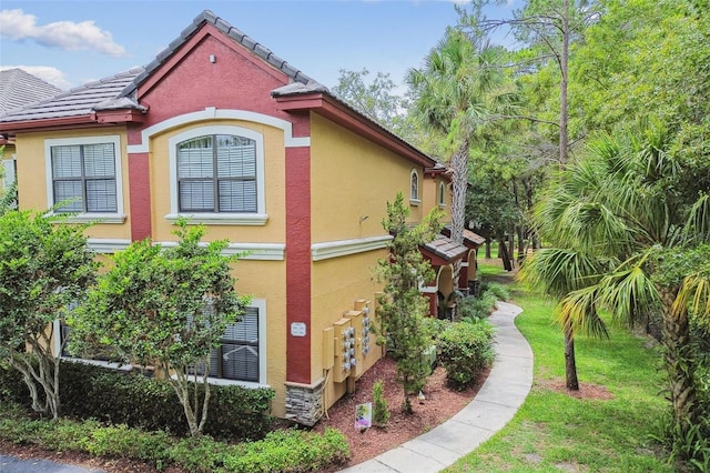 2171 Portofino Pl Unit 27-2725, Palm Harbor, FL 34683 - view of side of property featuring stucco siding, a yard, and a tiled roof