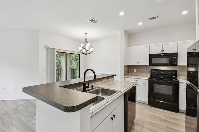 2171 Portofino Pl Unit 27-2725, Palm Harbor, FL 34683 - kitchen with black appliances, a sink, a chandelier, white cabinets, and a center island with sink