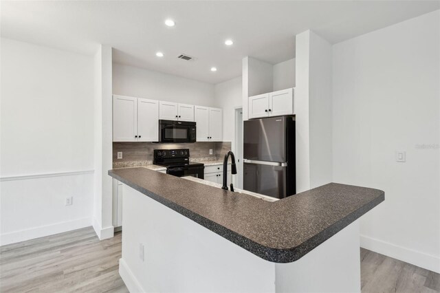 2171 Portofino Pl Unit 27-2725, Palm Harbor, FL 34683 - kitchen featuring black appliances, baseboards, light wood finished floors, dark countertops, and white cabinetry