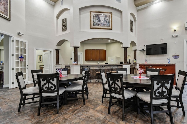 2171 Portofino Pl Unit 27-2725, Palm Harbor, FL 34683 - dining space with stone tile floors, a towering ceiling, decorative columns, and baseboards