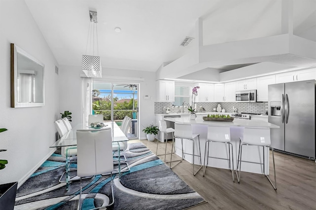 28 SW 21st Ave, Cape Coral, FL 33991 - kitchen featuring appliances with stainless steel finishes, backsplash, a breakfast bar area, light countertops, and white cabinetry