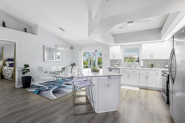 28 SW 21st Ave, Cape Coral, FL 33991 - kitchen featuring stainless steel appliances, a sink, light wood-type flooring, decorative backsplash, and lofted ceiling