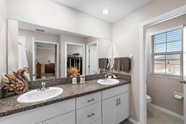 9334 Lemon Drop Loop, Sun City Center, FL 33573 - bathroom with double vanity, tile patterned flooring, toilet, baseboards, and a walk in closet