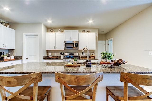 9334 Lemon Drop Loop, Sun City Center, FL 33573 - kitchen featuring appliances with stainless steel finishes, a kitchen breakfast bar, white cabinetry, recessed lighting, and a kitchen island with sink