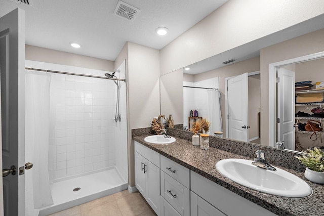 9334 Lemon Drop Loop, Sun City Center, FL 33573 - bathroom with double vanity, a tile shower, tile patterned floors, a spacious closet, and recessed lighting