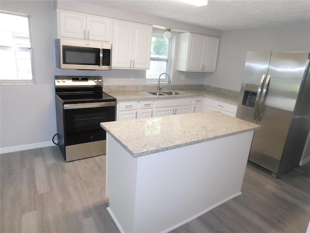 4417 Kohler St, New Port Richey, FL 34652 - kitchen featuring stainless steel appliances, a sink, light wood-type flooring, white cabinets, and a textured ceiling